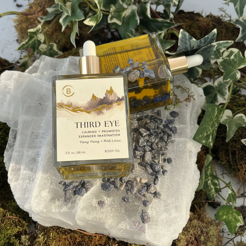 Two bottles of 'Third Eye' product on a rock with plants in the background