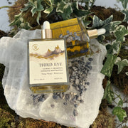 Two Third Eye Center Body Oil bottles on a rock with plants in the background