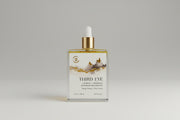 Bottle of Third Eye body oil with a gold dropper on a dark surface.