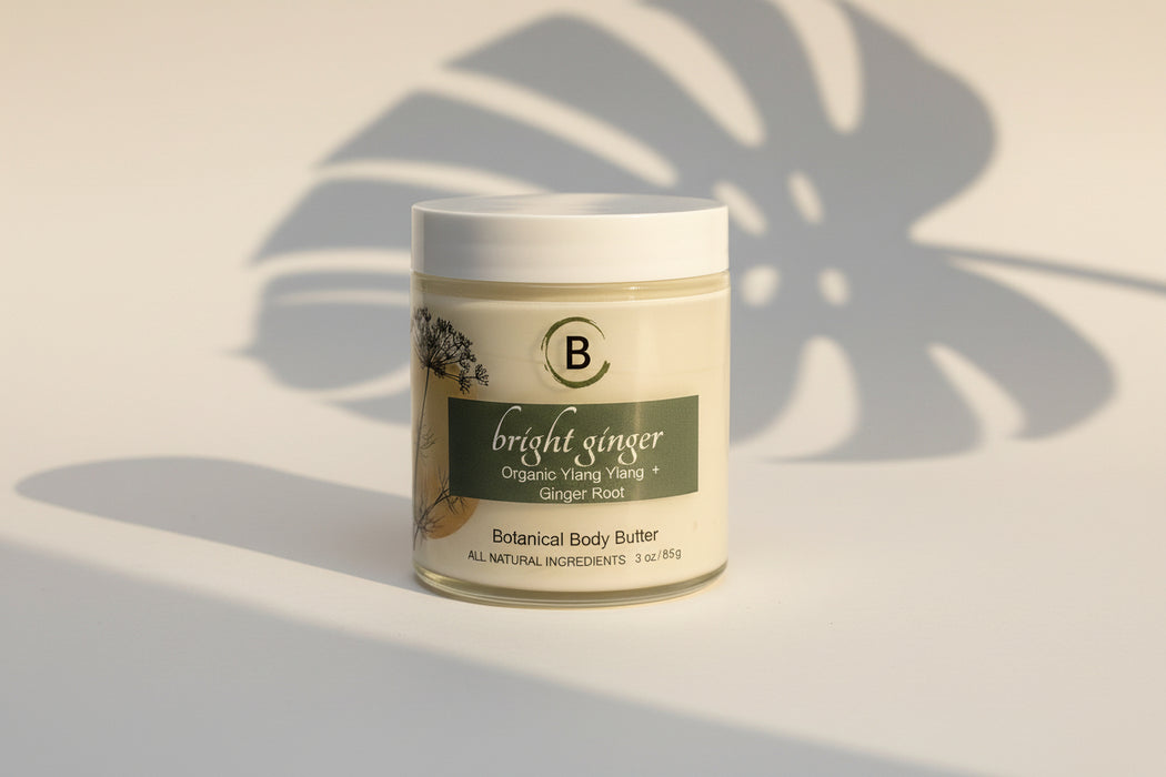 Jar of 'Bright Ginger' botanical body butter on a marble surface with light gray background.