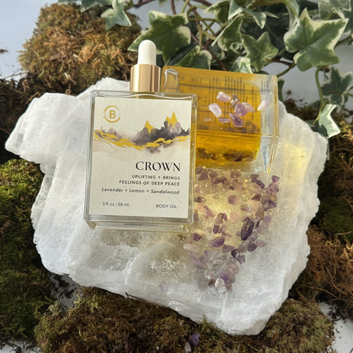 2 Crown Body Oil bottles on Crystal with Amethyst , moss and ivy surrounding it