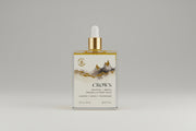 Bottle of Crown body oil with a dropper on a marble surface