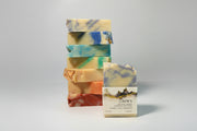 Stack of colorful soap bars with a single labeled Crown bar soap a gray background