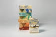 Stack of colorful soap bars with a single labeled Crown bar soap a gray background