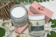 Jar of body butter with a pink soap bar on a textured surface.