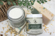 Two jars of skincare products with natural ingredients on a textured surface.