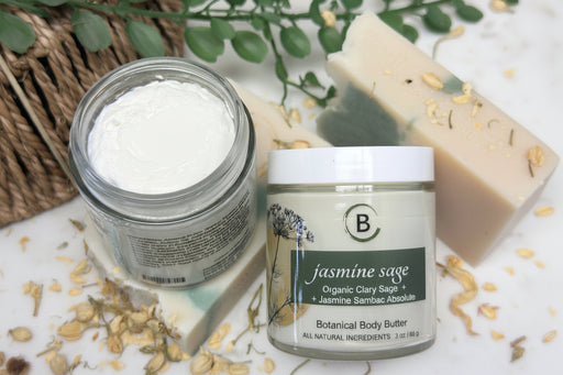 Two jars of skincare products with natural ingredients on a textured surface.