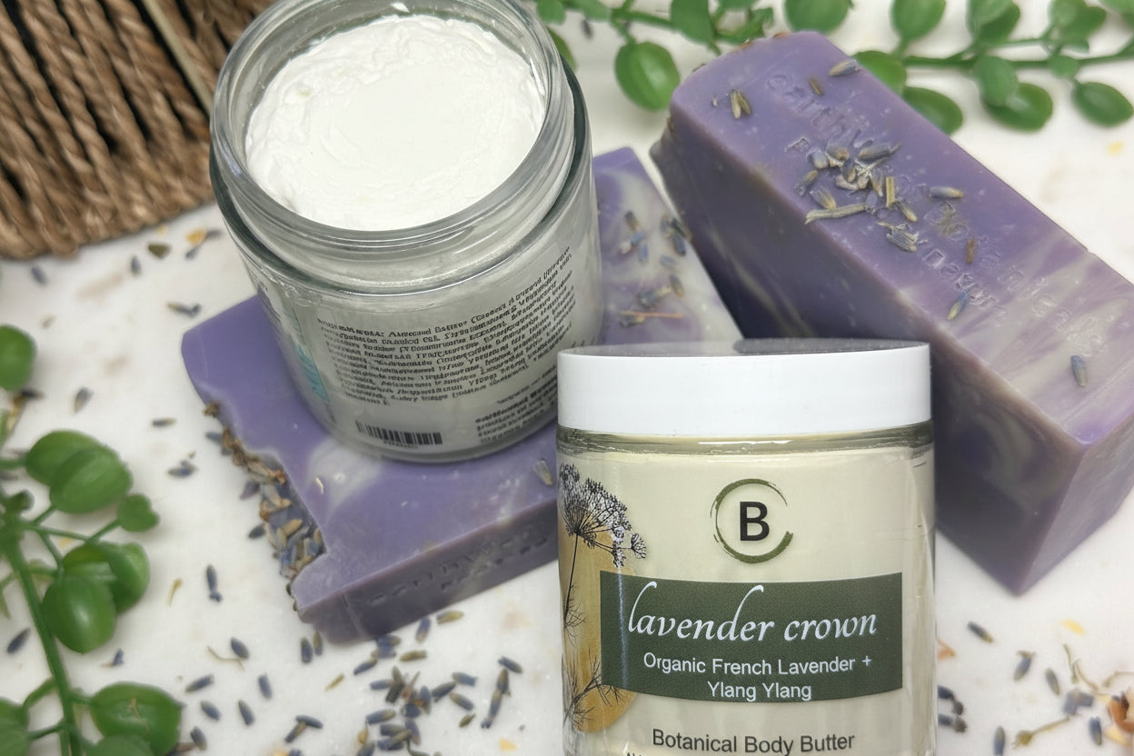 Lavender-themed skincare products including a jar of body butter, a jar of powder, and a bar of soap on a white surface with lavender leaves.