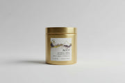 Gold candle container with a label on a blurred natural background