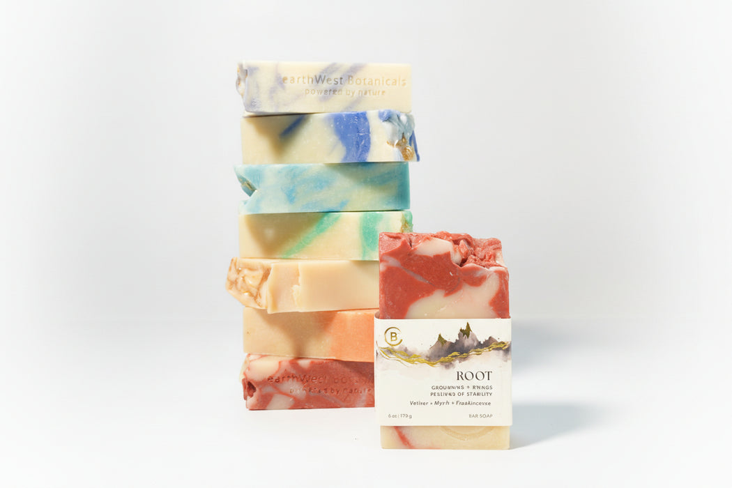 Stack of colorful soap bars with a single labeled Root bar soap a gray background