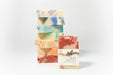 Stack of colorful soap bars with a single labeled Root bar soap a gray background