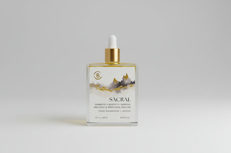 Body oil bottle labeled 'Sacral' with a dropper on a textured surface.