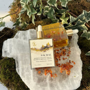 Two Sacral Center Body Oil bottles on a crystal with natural elements