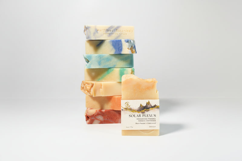 Stack of colorful soap bars with a single labeled Solar Plexus bar soap a gray background